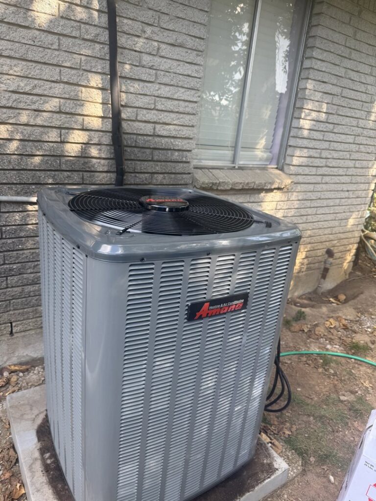 An Amana outdoor air conditioning unit installed next to a brick house by AirTech Solutions LLC in Broken Arrow, OK.