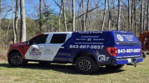 The American Air Solutions branded service truck, equipped with ladders, parked in a natural setting in Summerville, SC.