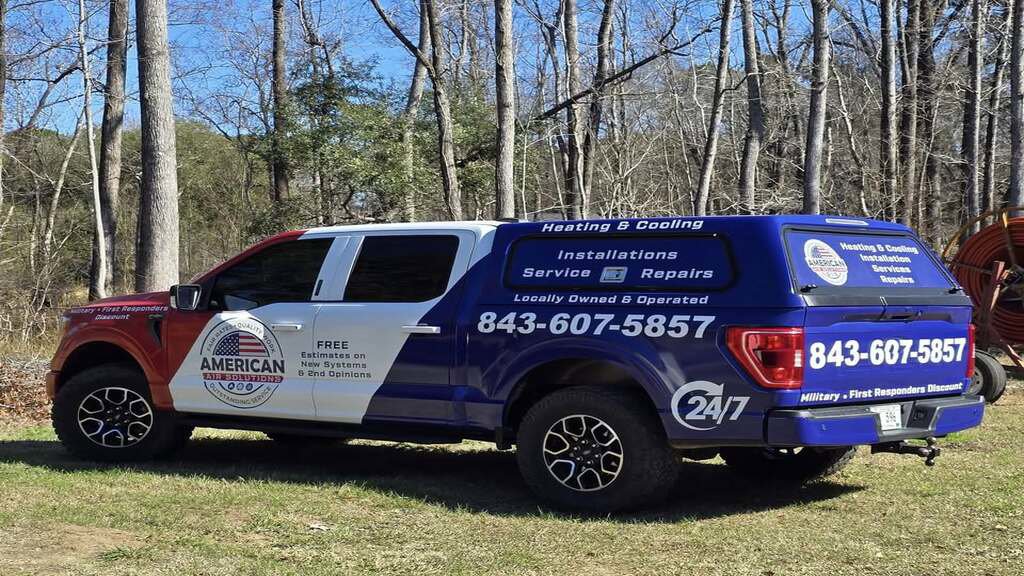 The American Air Solutions branded service truck, equipped with ladders, parked in a natural setting in Summerville, SC.
