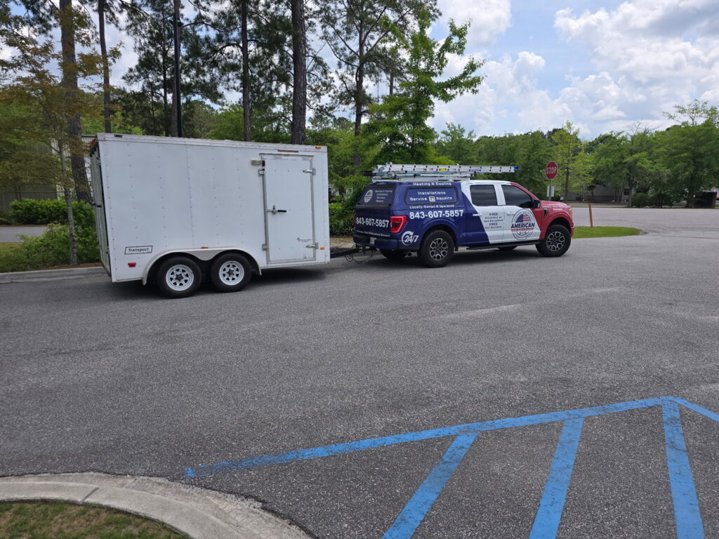 The American Air Solutions service truck towing an enclosed equipment trailer in a parking lot in Summerville, SC.