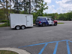 The American Air Solutions service truck towing an enclosed equipment trailer in a parking lot in Summerville, SC.