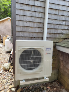 An American Standard Mitsubishi Electric outdoor HVAC unit installed on a shingled home by Maine Thermal Energy Services in Ellsworth, ME