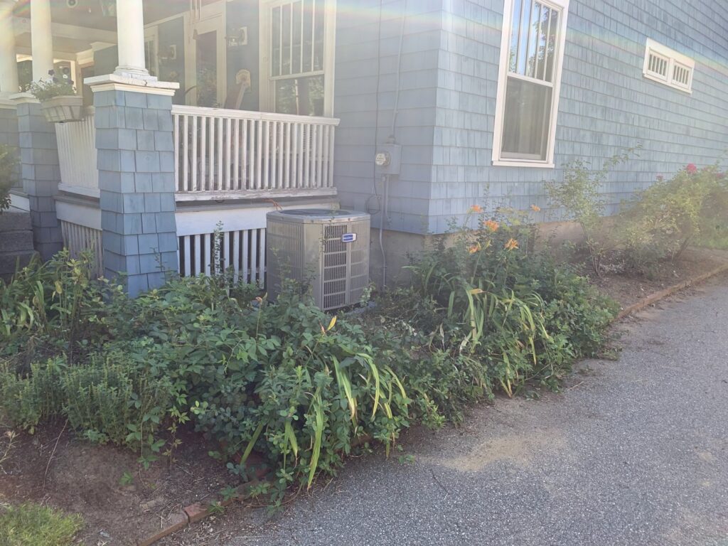 An American Standard outdoor air conditioning unit installed next to a house by Elite Mechanical in Manchester, NH.