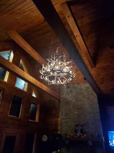 A large antler chandelier professionally installed and lit in a high-ceiling room by TD Electric in Waterbury, CT.