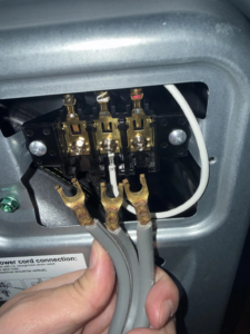 A hand connecting electrical wiring to appliance terminals, performed by Ask Electricians in Los Angeles, CA.