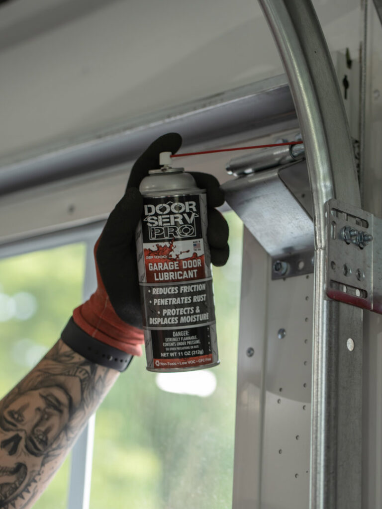 A technician applying Door Serv Pro brand garage door lubricant to tracks in Inwood, WV.