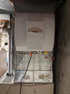 An Aprilaire whole-home humidifier installed on ductwork, showcasing a service by Your HVAC Guy in Aurora, IL.