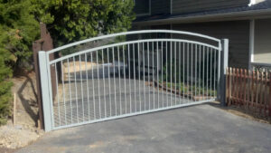 An elegant arched metal driveway gate installed at a residential entrance by Horizon Fence & Custom Gates, Inc. in Orangevale, CA.