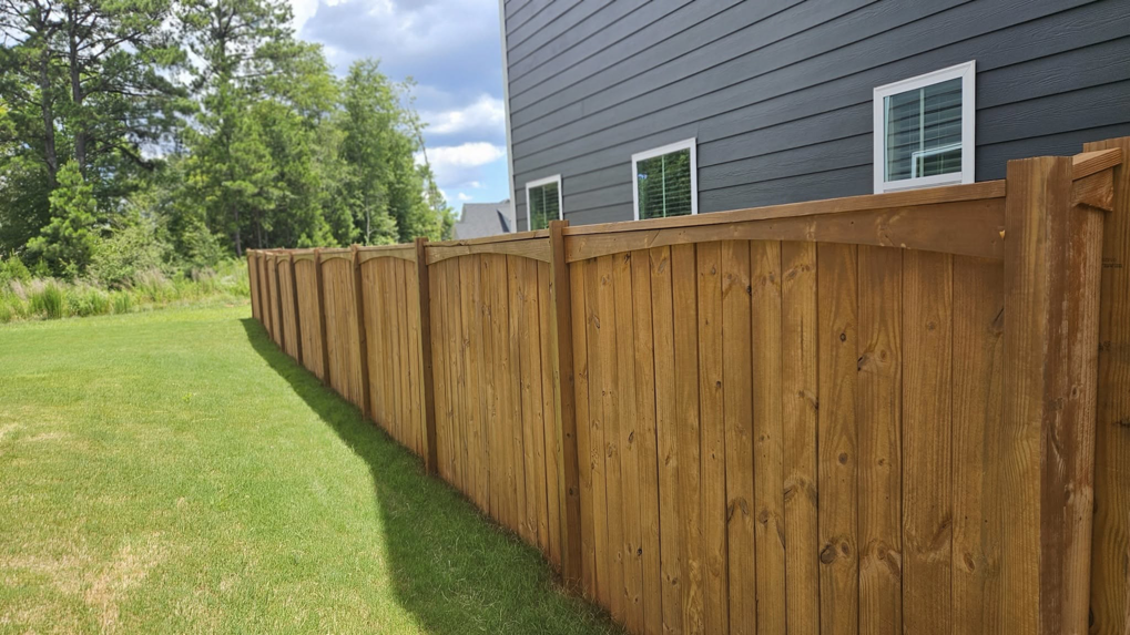 An elegant arched-top wood privacy fence installed next to a modern home by The Fence Guy One in Greenville, SC.