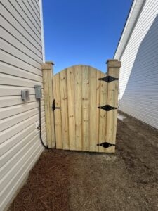 A custom arched wood gate installed between two houses by Charleston Fencing Services in Moncks Corner, SC.