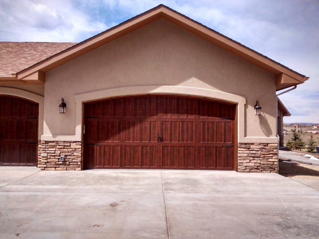 A beautifully installed arched wood-style garage door with decorative hardware by Mountain Fox Garage Doors in Colorado Springs, CO.