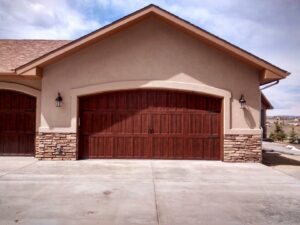 A beautifully installed arched wood-style garage door with decorative hardware by Mountain Fox Garage Doors in Colorado Springs, CO.