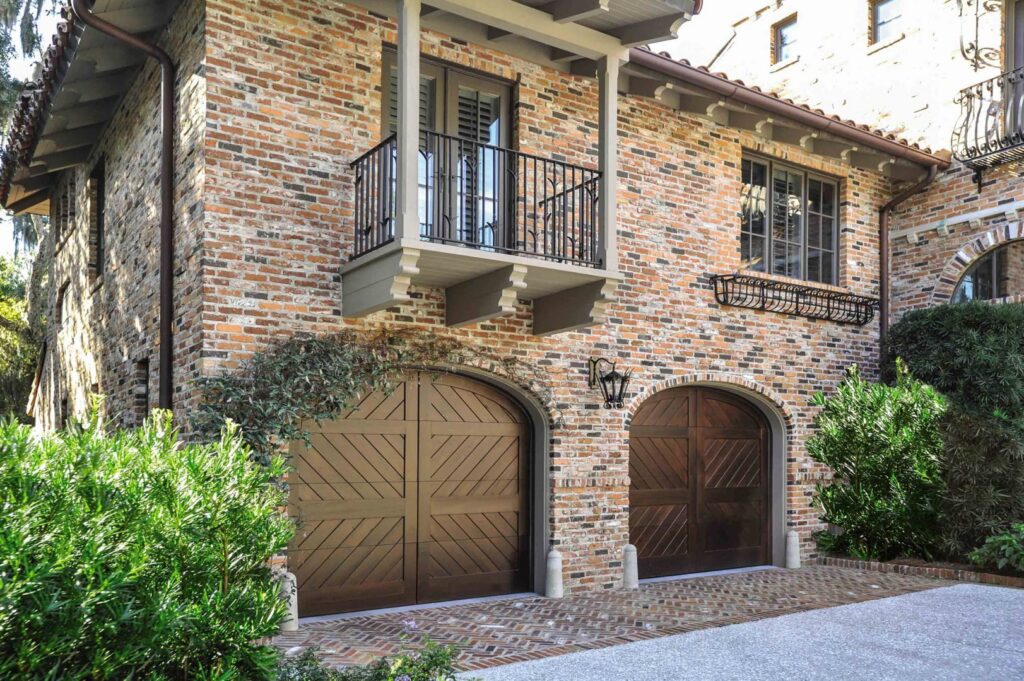 Arched wooden garage doors installed on a brick home by Overhead Door Company of Salem in Salem, OR.