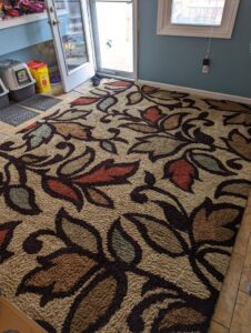 A large floral area rug on a tiled floor, ready for or after cleaning by Dewdrop Carpet Cleaning in Kansas City, MO.