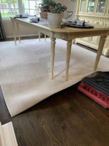 An area rug partially rolled up for cleaning in a dining room by S&J Carpet Care in Oswego, IL