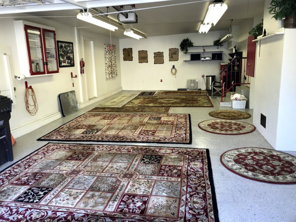 Various area rugs laid out in a garage, possibly for drying or inspection after cleaning by Mark it Clean Carpet & Upholstery Cleaning Long Beach, CA.