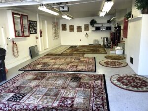Various area rugs laid out in a garage, possibly for drying or inspection after cleaning by Mark it Clean Carpet & Upholstery Cleaning Long Beach, CA.