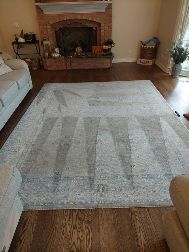 A large area rug on a hardwood floor showing distinct cleaning lines from a recent service by Proper Carpet Cleaning in Aurora, IL.