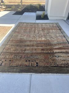 A large area rug laid out on concrete, likely undergoing cleaning or drying by Presto Carpet And Tile Cleaning in Brentwood, CA.