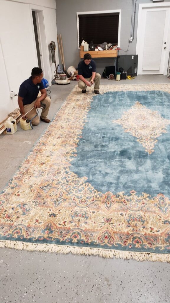 Two technicians professionally cleaning a large ornate area rug as part of services by Carpet Care in Reisterstown, MD.
