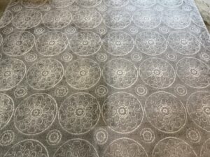 An area rug with a patterned design, showing a clear distinction between the cleaned and uncleaned sections by Heroic Carpet Cleaning Oregon in Beaverton, OR