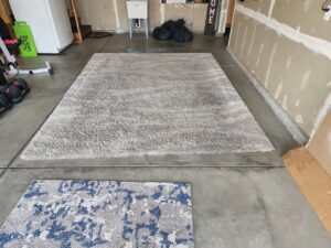 Two area rugs on a garage floor, possibly for cleaning or drying by Clean-Master in Coeur d'Alene, ID.