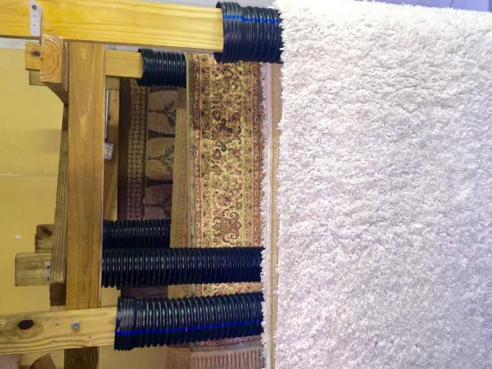 Various area rugs hanging on a drying rack after professional cleaning by Celtic Carpet Cleaner in Fort Lauderdale, FL.