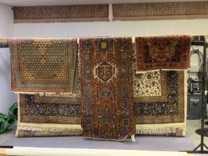 Several cleaned area rugs hanging on a drying rack after service at Mussallem Area Rug Specialist in Jacksonville, FL.