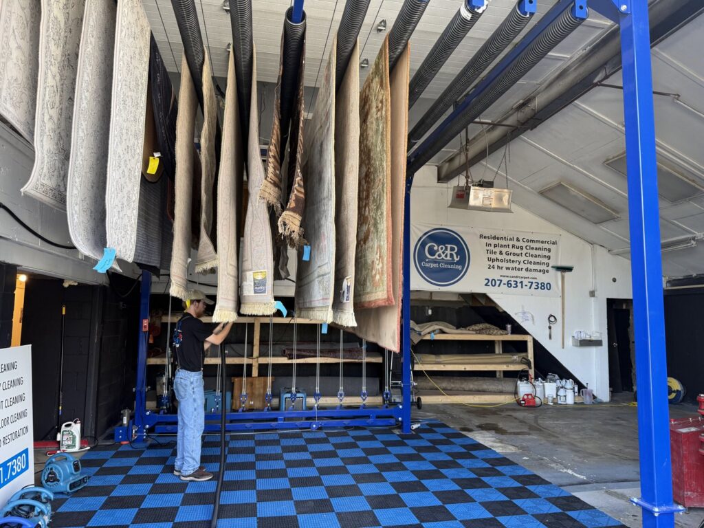 Several area rugs hanging to dry on a specialized rack after professional cleaning at C&R's Carpet Cleaning in Ellsworth, ME.
