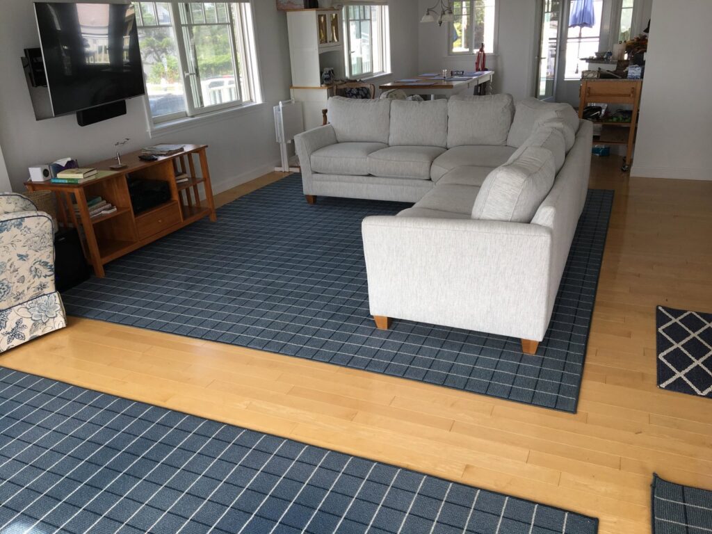 Multiple blue area rugs laid on a hardwood floor in a living room, a service offered by Yellow Finch Carpet Cleaning LLC in Dover, NH.