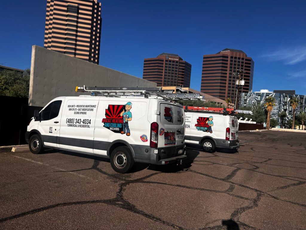 Two branded service vans for Arizaz Heating & Cooling parked in a commercial area in Chandler, AZ.