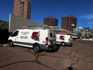 Two branded service vans for Arizaz Heating & Cooling parked in a commercial area in Chandler, AZ.