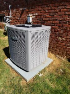 An Armstrong Air outdoor air conditioning unit installed next to a brick wall by C&L Heating and Air in Louisville, KY.