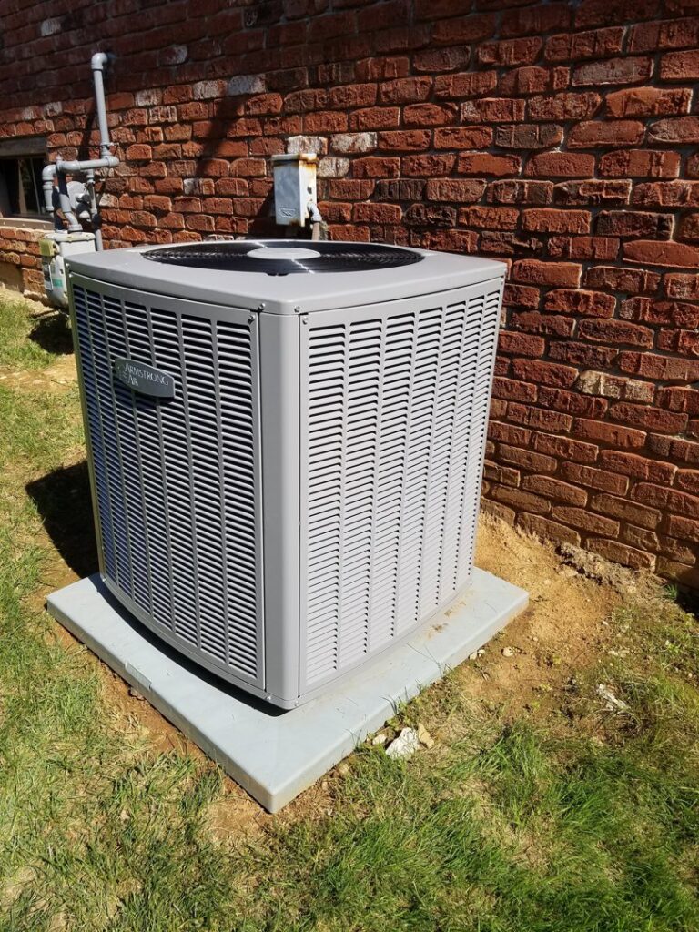 An Armstrong Air outdoor air conditioning unit installed next to a brick wall by C&L Heating and Air in Louisville, KY.