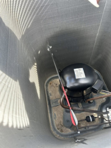 An arrow stuck inside the compressor unit of an outdoor AC system, indicating a repair job by Full Send Plumbing Heating & Cooling in Stillwater, OK.