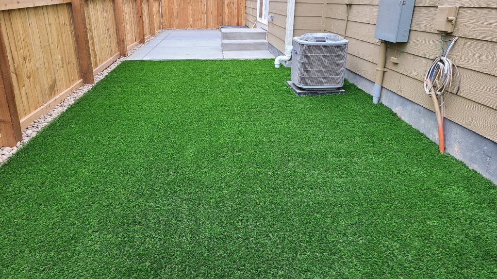 A newly installed artificial turf lawn next to a concrete patio by The Fisherman Landscaping LLC in Westminster, CO.