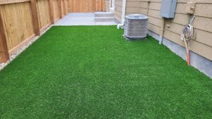 A newly installed artificial turf lawn next to a concrete patio by The Fisherman Landscaping LLC in Westminster, CO.