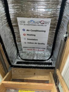 An attic access with a reflective insulation cover and a sign listing HVAC services by EZ Comfort Air Conditioning & Heating LLC in Humble, TX.