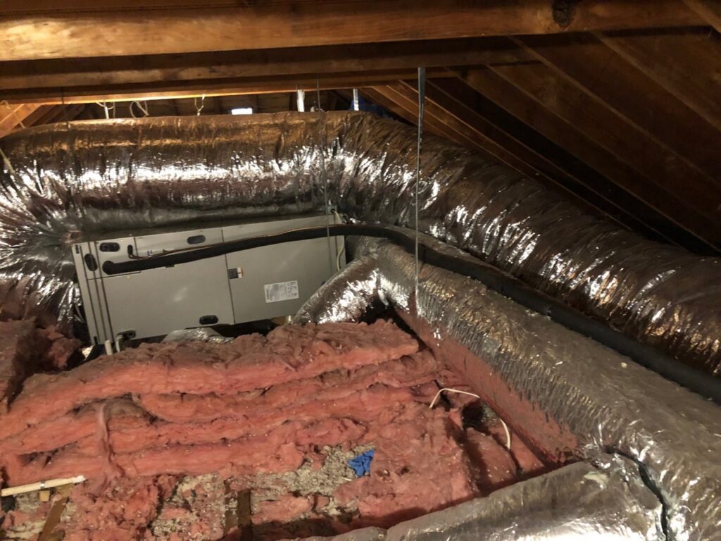 An attic air handler unit and insulated ductwork installed by HomeWorks Energy in Medford, MA.