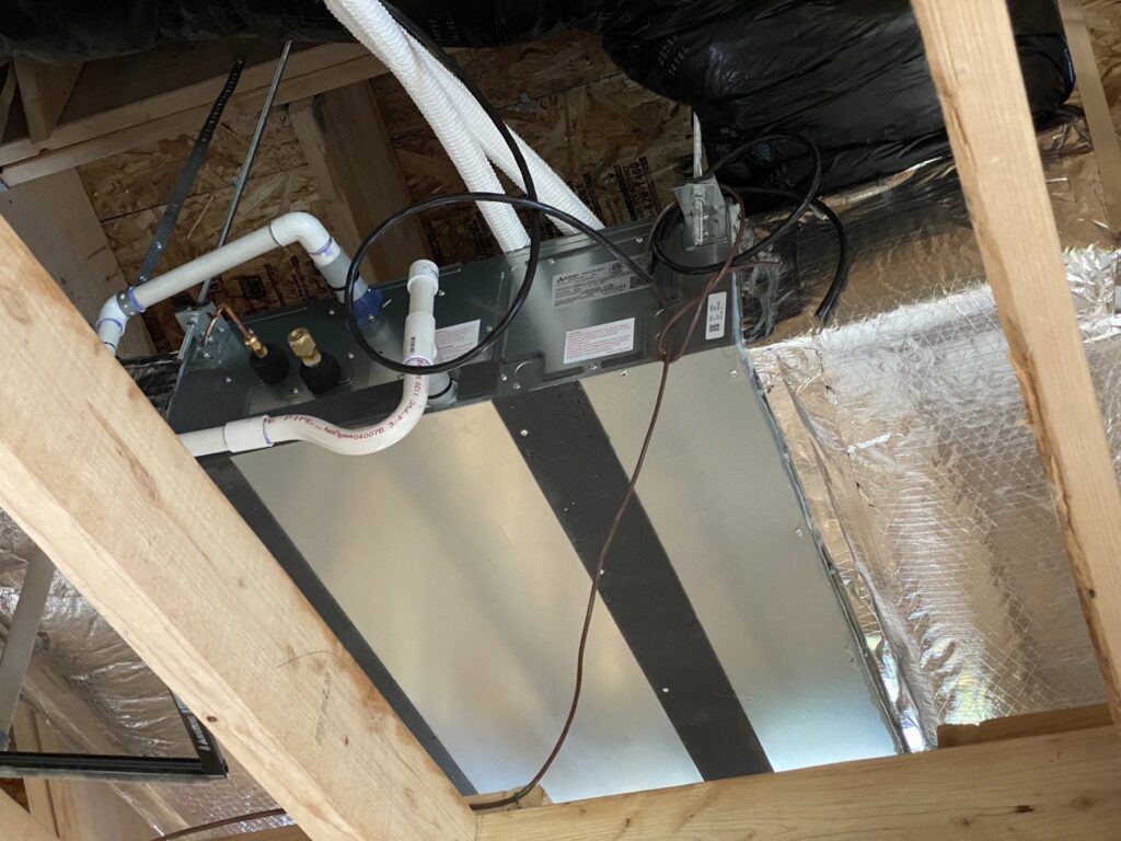 An air handler or coil unit with ductwork and condensate lines installed in an attic by Climate Control Experts HVAC LLC in Federal Way, WA