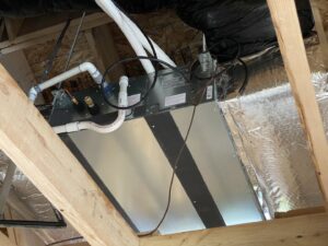 An air handler or coil unit with ductwork and condensate lines installed in an attic by Climate Control Experts HVAC LLC in Federal Way, WA