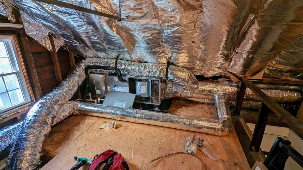 An air handler unit and extensive insulated ductwork installed in an attic by WARM Global HVAC in East Providence, RI