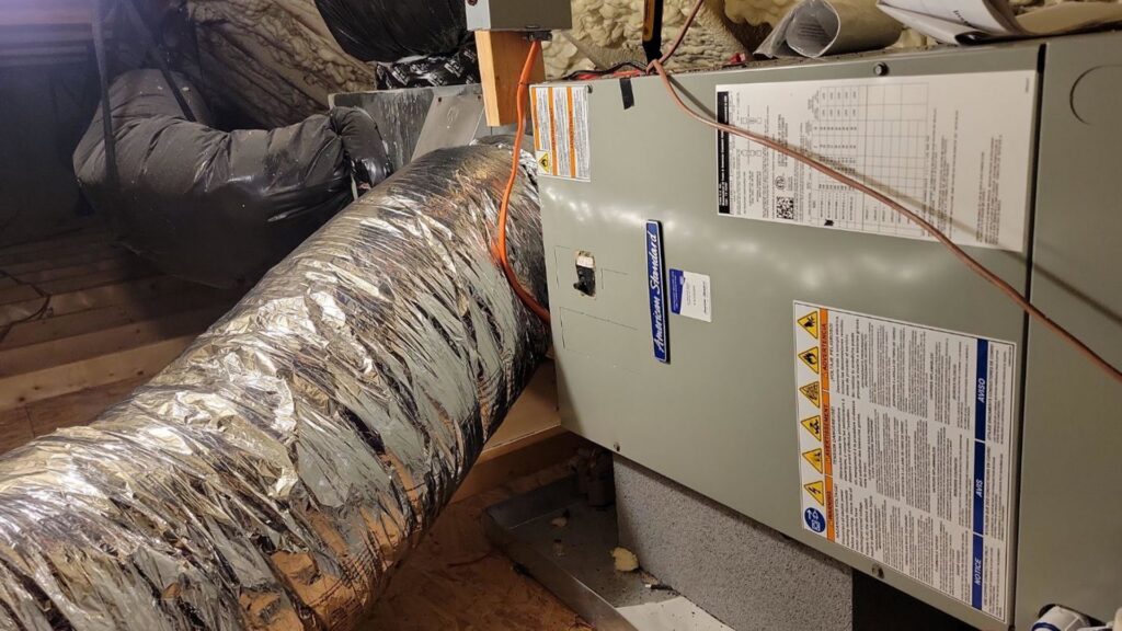 An indoor air handler and furnace unit with ductwork installed in an attic by Comfort Hounds Heating & Cooling in Raleigh, NC.