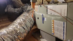 An indoor air handler and furnace unit with ductwork installed in an attic by Comfort Hounds Heating & Cooling in Raleigh, NC.