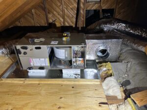 An indoor air handler unit with exposed components being installed or serviced in an attic by Climate Mechanical in Dinwiddie, VA.