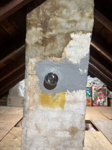 A chimney flue opening in an attic with new sealant applied by Certified Masons in Warwick, RI