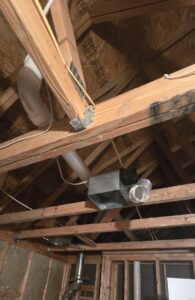 Electrical wiring and an exhaust fan installed in an attic space with exposed beams by Innovate Electric in Earth City, MO.
