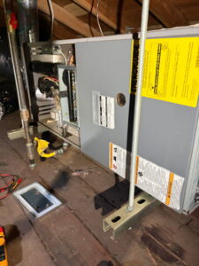 HVAC technician working on a furnace unit in an attic for HVAC Ministries LLC in Salem, OR