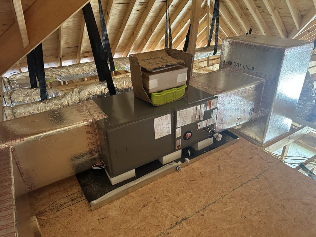 An HVAC air handler unit and insulated ductwork installed in an attic during new construction by Budget Heating and Air in Mobile, AL.