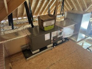 An HVAC air handler unit and insulated ductwork installed in an attic during new construction by Budget Heating and Air in Mobile, AL.